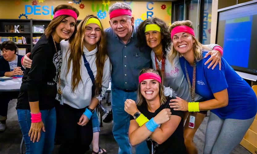 Teachers pose while wearing neon sweatbands